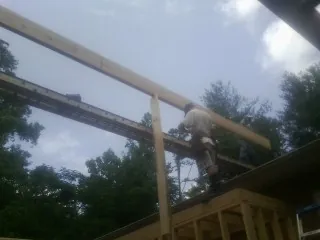 Carpenter setting a ridge beam over a new addition frame — Ice Dam Removal by Roofing Brothers in Bishopville