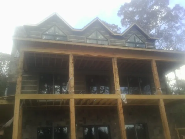 Dormers and porch framing on a large log home under construction — Roof Coating work by our crew in Bishopville