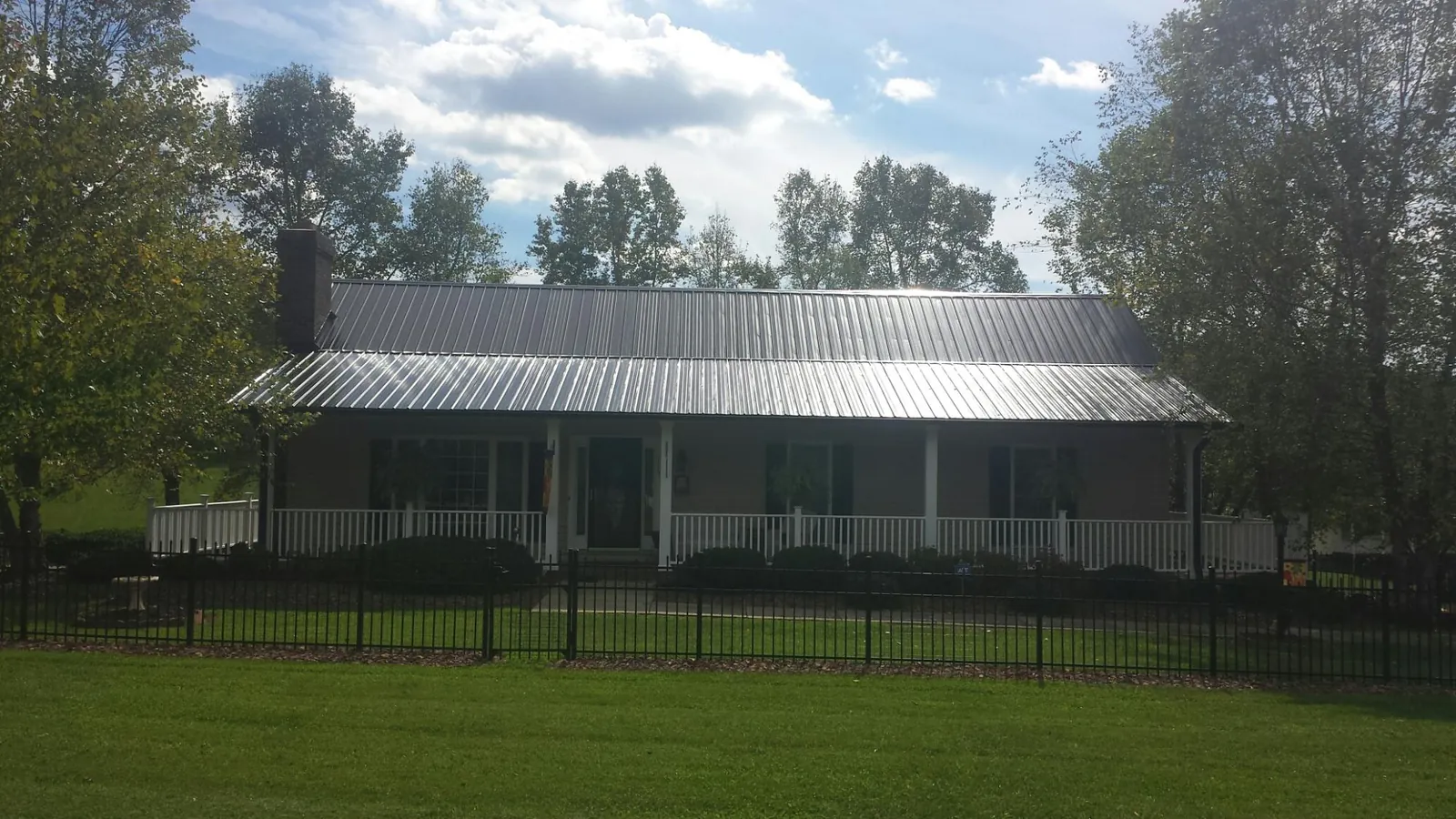 Gray metal roof on a brick ranch with a full width front porch — Gutter Guard Installation work by our crew in Bishopville